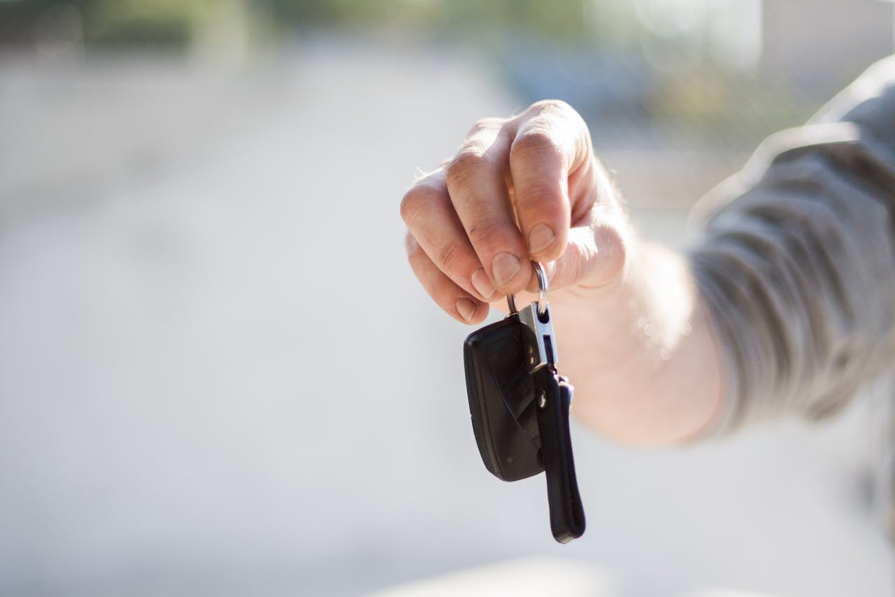 about-us Close-up of a hand handing over car keys, signifying purchase or rental.